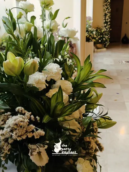 A detail shot of the elegant floral arrangements, featuring a mix of white tulips, carnations, and fresh greenery. I focus on using high-quality flowers to create a luxurious feel.