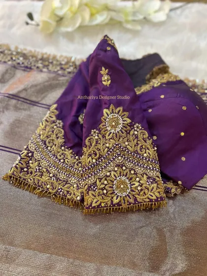 A royal purple blouse with intricate gold zardozi and pearl work on the sleeves.