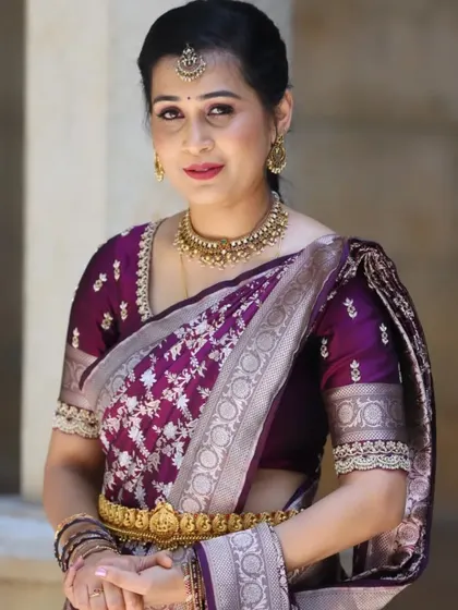 A simple and elegant portrait. The client's beautiful purple silk saree is paired with subtle makeup and a delicate smile.