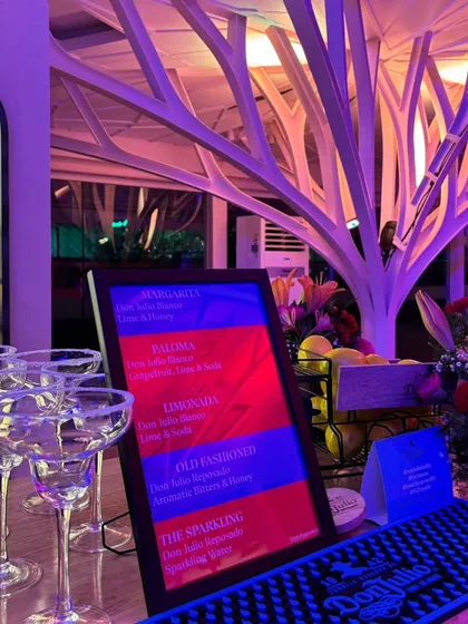 A close-up of the bar for the Don Julio event, featuring a custom menu of tequila cocktails like the Paloma and Margarita, with salt-rimmed glasses ready for service.