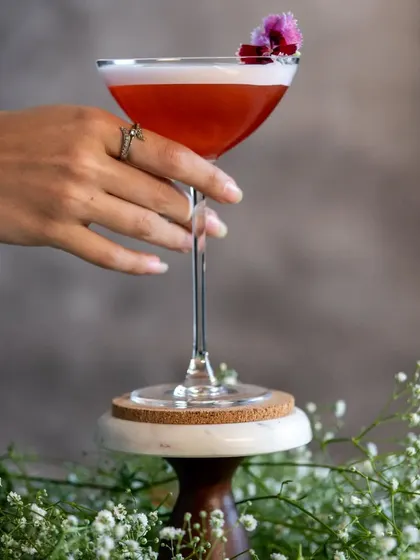 A festive holiday cocktail I call 'Santa’s Indulgence'. It's a mix of gin, house-made strawberry liqueur, rhubarb, and fresh lime, garnished with edible flowers.