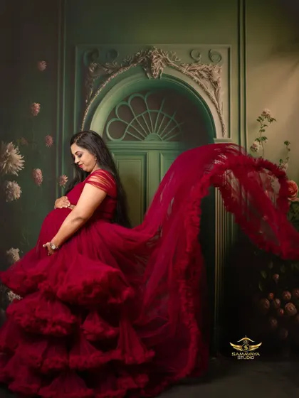 A profile view of the magnificent red gown, showing its flowing trail and rich texture against a painterly green backdrop.