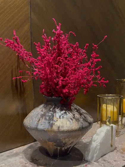 Sometimes, a single bold element is all you need. This striking arrangement of dried pink florals in a rustic vase makes a powerful statement.