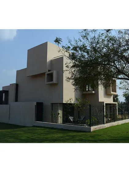 The exterior of a villa at Svamitva Terravana, showing the simple massing and earthy finish. The design focuses on creating comfortable, well-lit internal spaces that connect with nature.