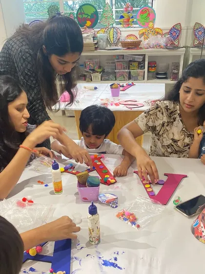 A busy table of moms and kids all working on their monogram art projects together. It's a fantastic group activity for a playdate or party.