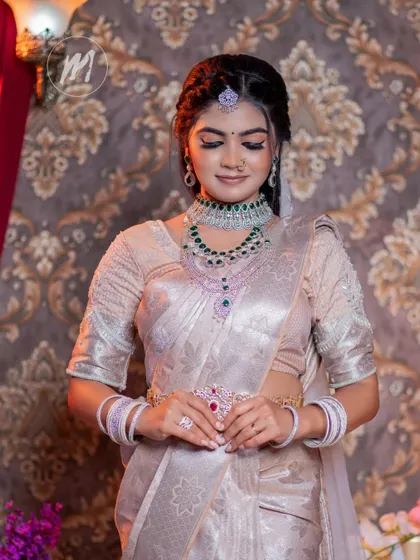 A contemplative pose that gives a closer look at the intricate blouse embroidery and the layered diamond and emerald necklaces.