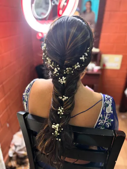 A classic fishtail braid on highlighted hair, delicately woven with sprigs of baby's breath for a romantic touch.