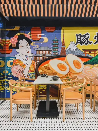 This Japanese restaurant design blends two distinct styles. One side features vibrant, graphic murals depicting iconic Japanese culture for a high-energy feel, while the other offers a calm, minimalist aesthetic for a more intimate dining experience.