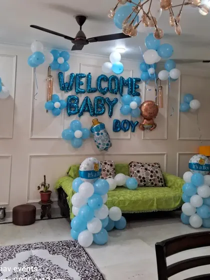 A wide-angle view of the living room decoration for a baby boy's welcome. You can see the wall decor, balloon pillars, and balloons scattered on the ceiling.