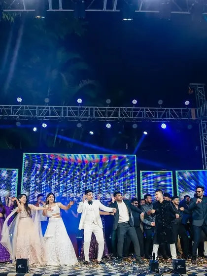 A wide shot of the entire Sangeet performance, showing the couple, backup dancers, and the grand stage setup.