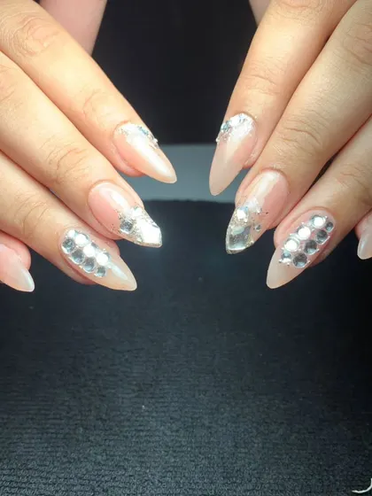 An elegant and luxurious design featuring a nude base on stiletto nails. The look is enhanced with silver mirrored crystals arranged in a sophisticated pattern on accent nails.
