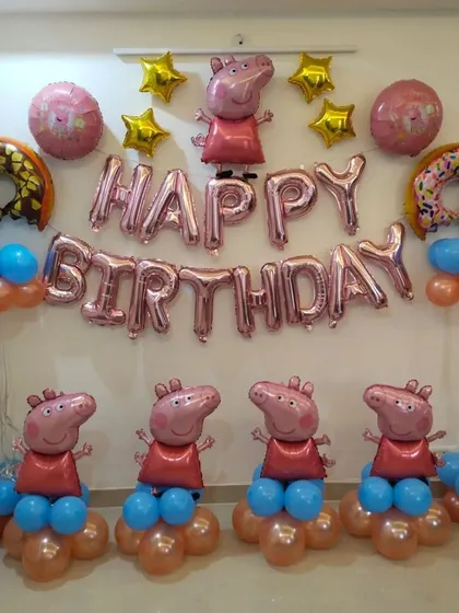 A cute Peppa Pig room decoration. This setup includes multiple Peppa Pig character foil balloons, donut-shaped balloons, and "Happy Birthday" foil letters on the wall.