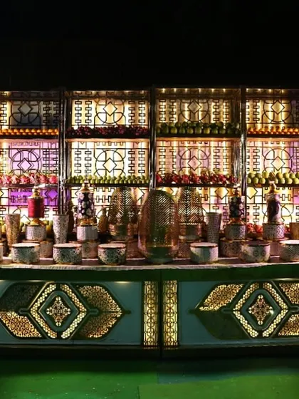 A grand and opulent beverage station. The intricately designed, backlit counter and shelving create a spectacular display for a wide array of drinks, making it a definite highlight of the event.