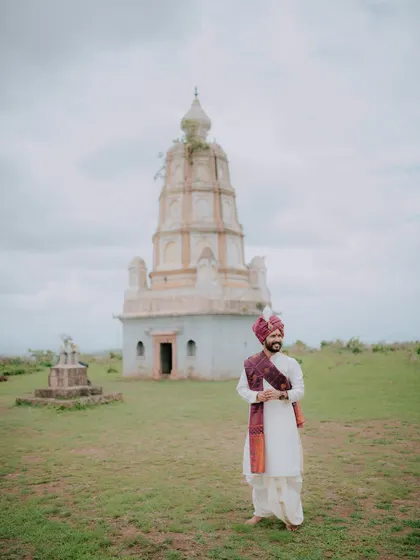 A portrait of the groom standing before an ancient temple, blending tradition with scenic photography.