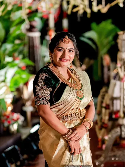 A full-length view of our client at a wedding event, looking regal in her green velvet embroidered blouse and gold saree. The entire ensemble speaks of timeless artistry and meticulous craftsmanship.