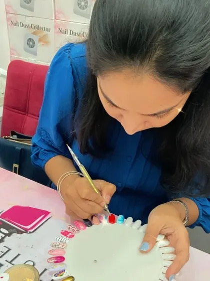 A student adds a pop of color to her practice wheel, learning how to create vibrant and eye-catching nail art.