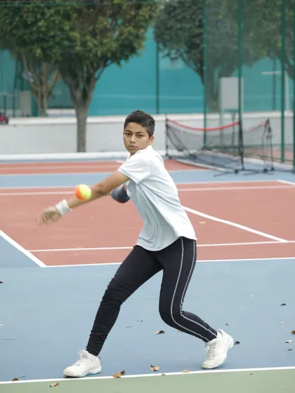 This young player is honing his skills with an orange ball. This stage is crucial for developing control, learning to judge the bounce, and executing groundstrokes with proper form before moving to the full-size yellow ball.