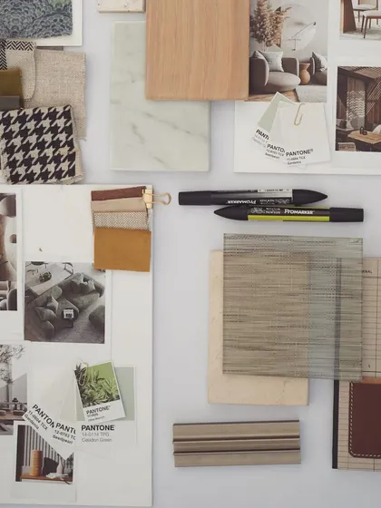 This image captures the beautiful paraphernalia that goes into designing a space. A moodboard with fabric swatches, material samples, and inspiration photos sits on a desk, ready to guide the creative process.