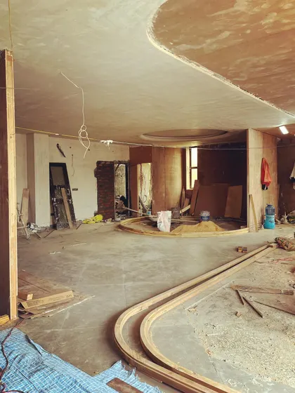 Another view of the micro-office in progress, showing the sweeping curves of the wooden partitions and ceiling details. These elements are designed to create a dynamic and organic feel within a small footprint.