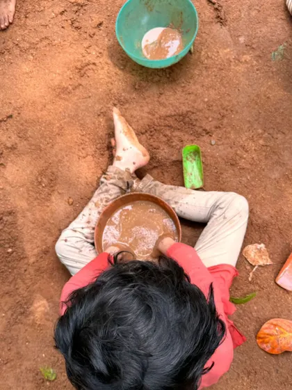 An overhead view of a child fully immersed in mud play, a rich sensory experience that is both calming and creatively stimulating.