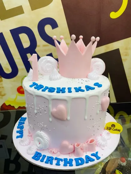 A pretty pink 2.5kg first birthday cake with a princess crown and white chocolate drip.