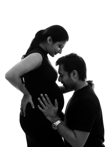 A powerful and intimate silhouette of a dad-to-be kissing his partner's belly, rendered in classic black and white.