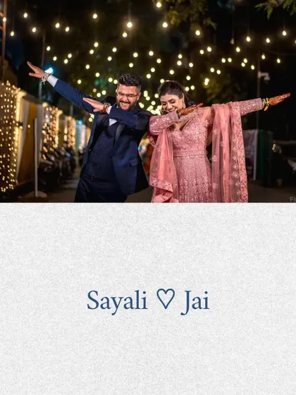 A fun and quirky pose from the couple under beautiful string lights, showing that your reception photos can be both elegant and playful.