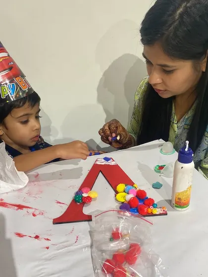 A little artist in a birthday hat, completely focused on decorating his monogram letter. It's so wonderful to see kids express their creativity and feel proud of their work.