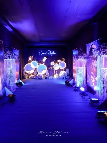 The entrance walkway to the 'Cosmic Rhythm' sangeet, lined with futuristic light installations and astronaut-themed art panels, creating an otherworldly experience.