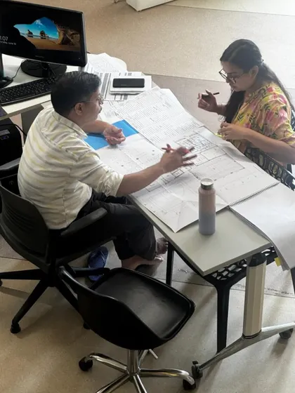 Two team members discussing architectural plans. This image highlights the mentorship and collaborative learning that is a core part of our studio culture.