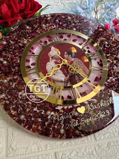 The combination of a soft pink background with deep red petals gives this clock a romantic feel. Pearls are scattered throughout to add a touch of elegance.