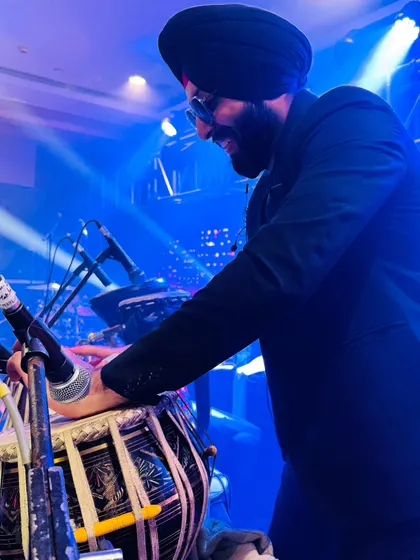 A side profile shot capturing a moment of joy during a live wedding performance. The blue stage lighting adds to the vibrant atmosphere.
