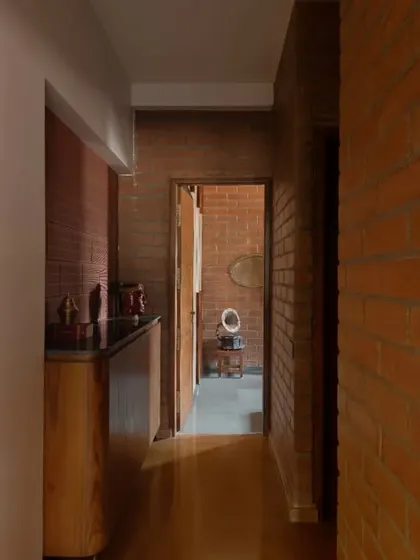 A view down a corridor in the Madhura house, showing the transition between different material palettes, from the yellow oxide living room to the brick-lined passages.