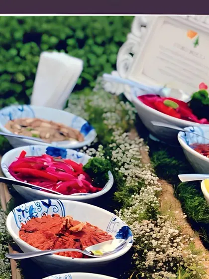 A vibrant display of fresh dips and salads. This station features a variety of options, including a creamy hummus, a spicy muhammara, and pickled onions, all beautifully presented amidst a bed of baby's breath.