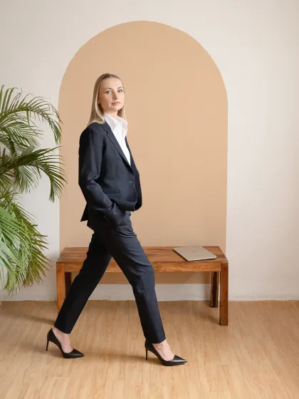 A professional portrait for a business leader, set in a minimalist studio. The focus is on conveying confidence and approachability through clean lines, natural posture, and direct engagement.