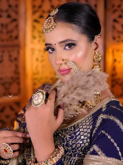 A close-up portrait of a bride in a unique blue lehenga. The focus is on her expressive face and the traditional jewellery that complements the modern outfit.