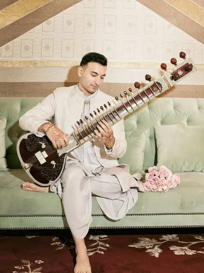 A serene moment playing the sitar, barefoot, in a beautiful indoor setting.