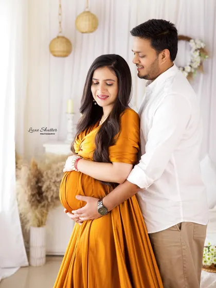 A warm and gentle maternity portrait. The mustard-colored dress and the soft studio lighting create a cozy and intimate atmosphere.