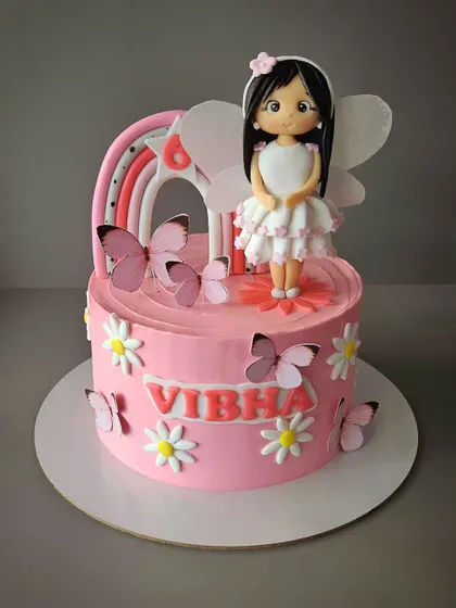 A cake with a fairy, butterflies, rainbow, and flowers for Vibha's 6th birthday. This pink vanilla cake is a whimsical garden party in edible form.