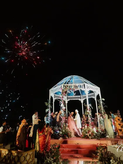 The wedding mandap lit up by a spectacular firework display against the night sky. We coordinate these grand moments to create a truly cinematic experience for you and your guests.