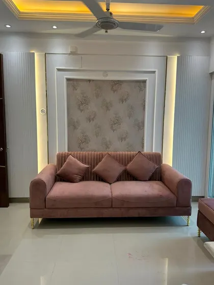 A full view of the living area with our custom pink sofa as the centerpiece. The design shows how a single, well-crafted furniture piece can define the aesthetic of an entire room, complemented by integrated wall lighting.