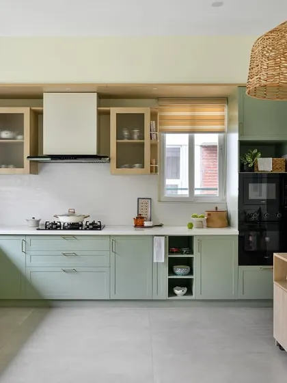 This kitchen from our 'House of Kismish' project exudes a European cottage vibe with its sage green cabinetry and delicate piccolo tiles. The design includes open shelving and a dedicated breakfast nook.