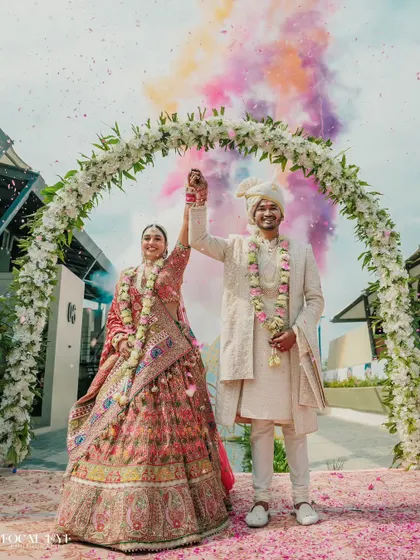 The couple's triumphant exit through a floral arch, marked by a burst of colorful smoke. This is the perfect final shot for a wedding ceremony.