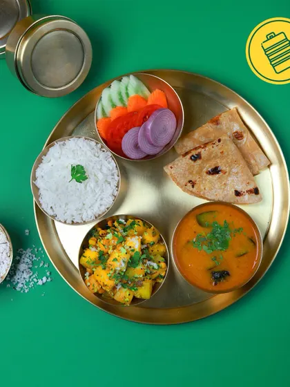A vibrant green background makes this simple thali of potato sabzi, sambar-style dal, rice, roti, and salad pop. It's a feast for the eyes and the stomach.