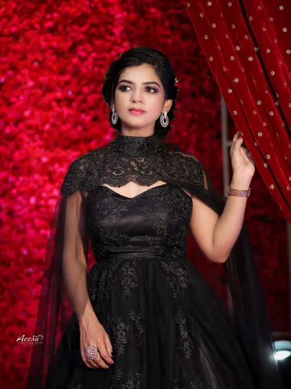 A slightly different angle reveals more of the intricate lace detail on the gown. The contrast between the black dress and the vibrant red backdrop is visually striking.