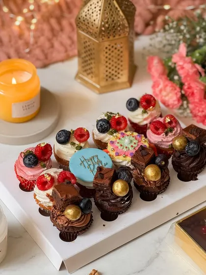 A box of twelve assorted mini cupcakes, beautifully decorated with fresh berries, chocolate, and a "Happy Rakhi" plaque. These bite-sized delights are perfect for sharing and celebrating together.