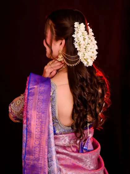 A view of the traditional South Indian bridal hairstyle, featuring long, flowing curls adorned with fresh gajra. This style adds a touch of romance and elegance.