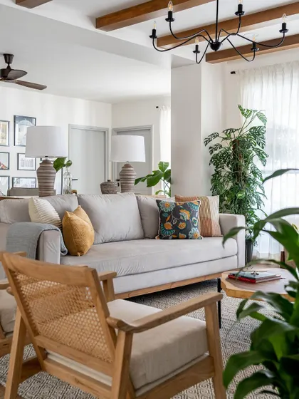 A bright and airy living room from 2023, with exposed beams, comfortable seating, and lots of greenery.