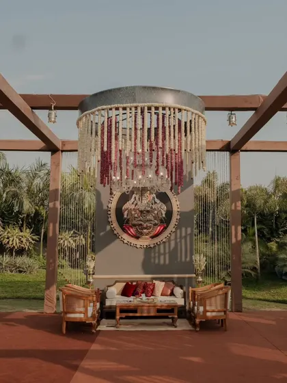 A standalone lounge seating setup under a grand floral chandelier, creating an intimate and luxurious conversation spot within a larger event space.