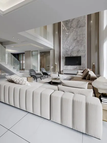 A double-height living room that exudes grandeur. We used a floor-to-ceiling marble feature wall for the TV and a statement channel-tufted sofa to anchor this breathtaking space.